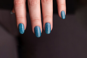 Female hand with beautiful manicure - blue glitter nails. Nail care concept