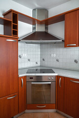 A kitchenette with a stove and hood in the modern kitchen of the apartment