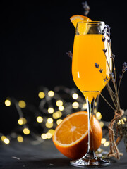 mimosa cocktail with orange juice and champagne. Orange slice and bokeh garlands