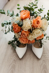 White Heels Filled With Orange Flower Bouquet
Simple white heels with a bouquet of beige, orange roses, and green details laying on the floor