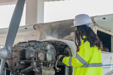 Fototapeta premium Technician fixing the engine of the airplane,Female aerospace engineering checking aircraft engines,Asian mechanic maintenance inspects plane engine