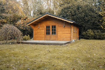 Beautiful forest hut for holidays in the forest. Garden shed with yellow leaves and trees in late autumn. Autumn mood in the country. 