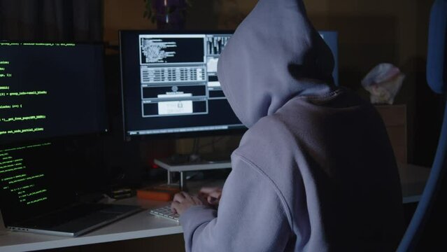 Young hacker, working and hacking with his computers. Attacking systems and danger computering.