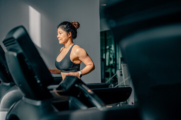 Fototapeta premium Side view of Asian women running or jogging on treadmill at gym.sport indoor burn weight and strong health.Fitness healthy lifestyle and workout concept.
