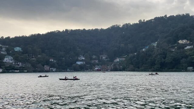 Boats flowing in Nainital (Naini) lake forested hill background Kumaon, Uttarakhand, India