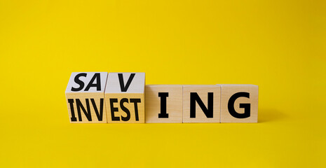 Saving and Investing symbol. Turned wooden cubes with words Investing and Saving. Beautiful yellow background. Business and Saving and Investing concept. Copy space