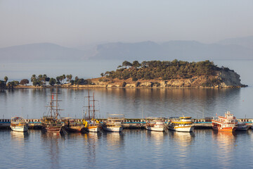 Fototapeta na wymiar Boats at Marina on the Coast in a Touristic Town by the Aegean Sea. Kusadasi, Turkey. Sunny Morning Sunrise.