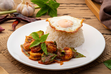 Stir Fried Shrimp with Curry Paste and cooked rice topped with fried egg in white plate