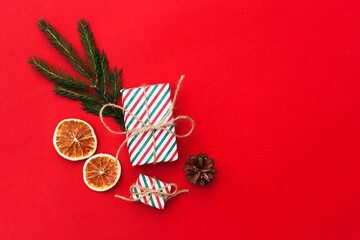 Christmas composition with eco crafted gift, dried orange, cone, xmas tree fir branch, gift and wood star. Natural minimal new year concept, top view, flat lay, isolated, copy space on red background