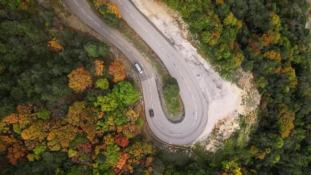 Aerial view of the winding road with cars passing in the mountains. Aerial View Above Top view colorful Autumn Forest.Aerial Top View Over Straight Road With Cars in Colorful Countryside Autumn Forest