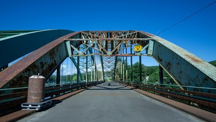 Steel arch bridge under a clear blue sky with some rust
