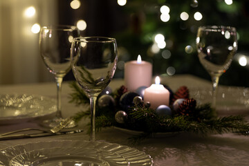 Serving the festive table. Food and drinks, plates and glasses. Evening lights and candles. Christmas dinner on Christmas Eve and New Year's Eve.
