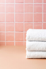 Obraz na płótnie Canvas White cotton towels on table inside a bathroom wall tiles ceramic background. Copy space