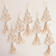 Christmas tree macrame toys on craft papper. White background. Natural materials - cotton thread, wood beads and stick. Eco decorations, ornaments, hand made decor. Winter and New Year holidays.