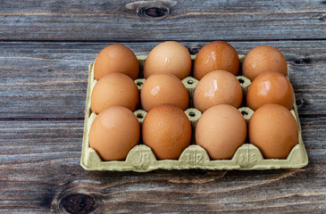 Close up.  Dozen fresh eggs in carton box, on rustic wooden background.