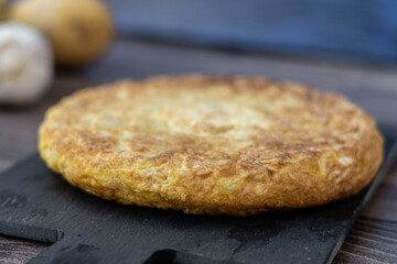 Close up, detailed. Spanish potato omelette with some ingredients, on a wooden background.