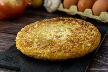 Close up, detailed. Spanish potato omelette with some ingredients, on a wooden background.