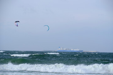 Kitesurfing, riding board waves during storm holding to flying kite.