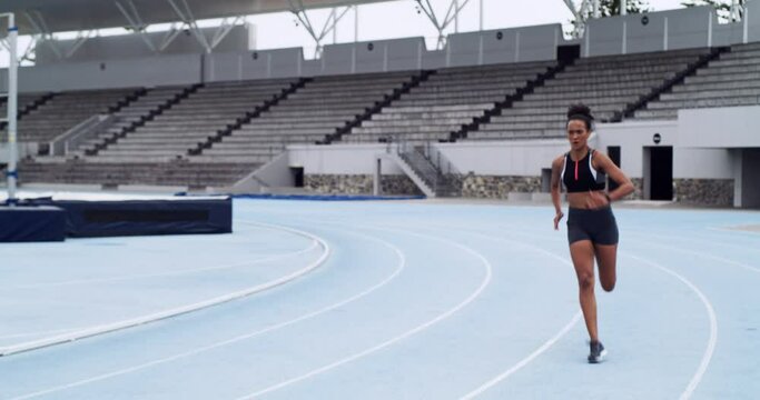 Fitness, woman and running at stadium track for exercise, workout or training for race or sprint competition. Active and competitive female athlete runner sprinting in sports athletics for practice
