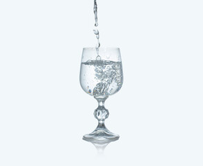 Filling wine glass with water on white background