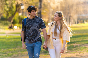 Young heterosexual couple walking in a park and looking each other