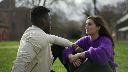 Black man and white girlfriend dating sitting outside in grass. Interracial couple together