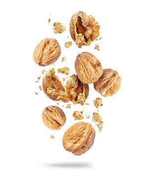 Whole and crushed walnuts close-up in the air on a white background
