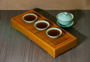 Cups, chaban selective focus. Gongfu cha tea ceremony. Zhu-yao Chinese ceramics on a bamboo tea board. Brewing Chinese tea in ceramic dishes gaiwan, chahai, cups during the tea ceremony close-up.