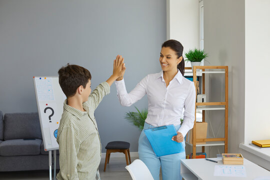Woman professional psychologist high five with smile to teen boy her patient on the end of therapy session. Psychological help, psychotherapy, therapy, support for teens concept. Child psychologist.