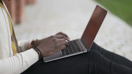 African man in front of laptop computer working remotely outside