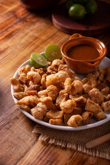 Chicharrones. Deep fried pork rinds, crispy pork skin pieces, traditional mexican ingredient or snack served with lemon juice and red hot chili sauce.