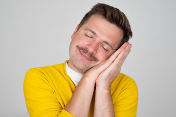 Caucasian man sleeping on pillow smiling, having rest after hardworking day