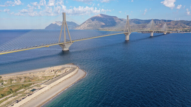 Aerial drone photo of iconic medieval ancient castle of Rio built next to modern cable strait bridge of Harilaos Trikoupis crossing corinthian Gulf, Central Greece