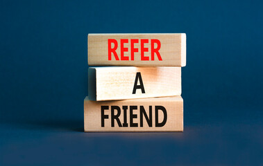 Refer a friend symbol. Concept words Refer a friend on wooden blocks on a beautiful grey table grey background. Business and refer a friend concept. Copy space.