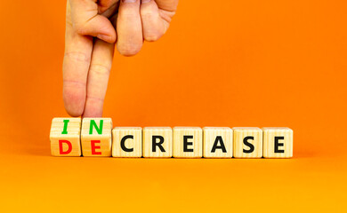 Increase or decrease symbol. Concept words Increase and Decrease on wooden cubes. Businessman hand. Beautiful orange table orange background. Business increase or decrease concept. Copy space.