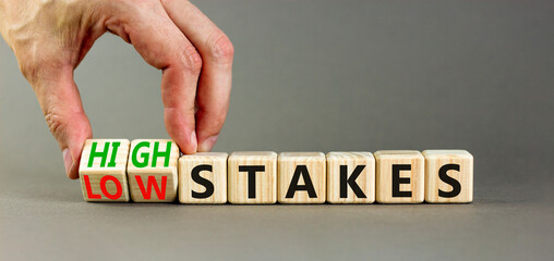 High or low stakes symbol. Concept words High stakes and Low stakes on wooden cubes. Businessman hand. Beautiful grey table grey background. Business high or low stakes concept. Copy space.