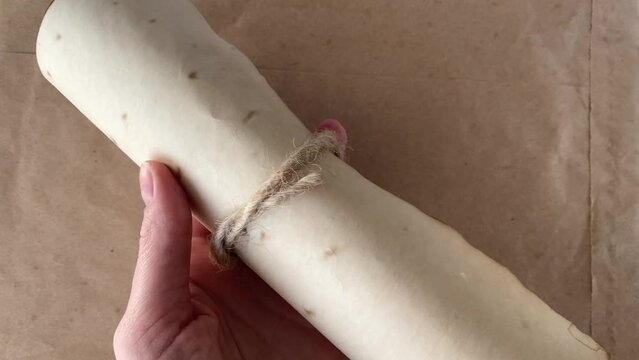 Ancient Scroll. Medieval manuscript on a beige background in the hand of a woman