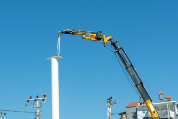 Installing a white pole support with a crane in the city.