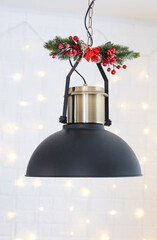 The black lampshade in the industrial loft style is decorated with spruce branches for Christmas...