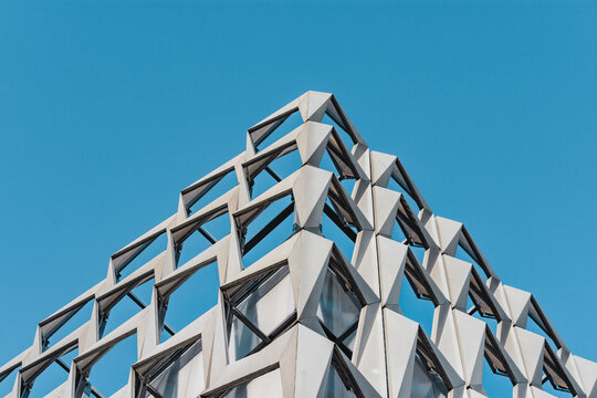 Futuristic architectural design in line art style. Tiled structure looks like an abstract pyramid against blue sky