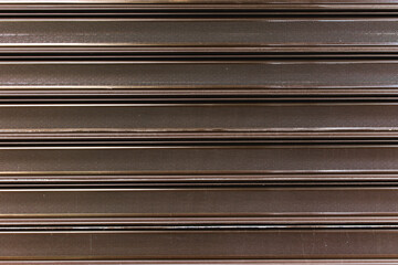 Detail shutter roller of a garage door made of metallic material or steel in dark cognac color....