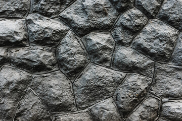 Dark colored wall made of stones and cement. Masonry backdrop