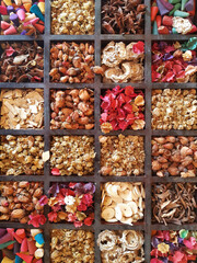 Background of wooden organizer container with variety of dried flowers and spices. Wooden box with multicolored flowers. Wellness decoration details, massage environment. Zen atmosphere. Aerial view.