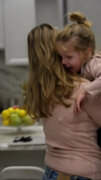 Busy young mother is trying to work remotely on laptop with screaming, crying little daughter. Young woman tries to distract her little daughter from hysterics and takes her away to calm her down