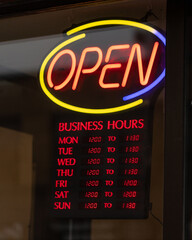 Open business hours sign on restaurant door.