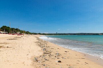 Jimbaran beach with famous fish restaurants and a lot of different garbage on the sand.
