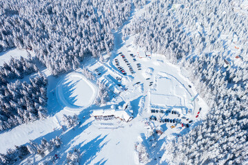 Flying over a beautiful ski resort surrounded with the forest on the mountain
