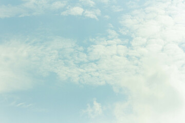 White clouds in blue sky with bright glare of sun.