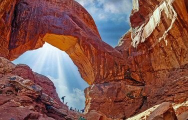 Beautiful spectacular red sandstone arch window cliff landmark, unrecognizable people group, blue...