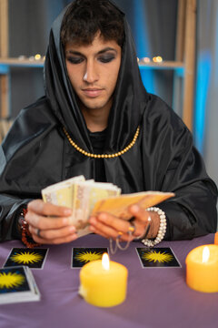 Male Fortune teller reading a future by tarot cards in the light of candle concept.